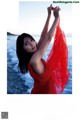 A woman in a red dress standing on the beach.