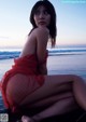 A woman in a red dress sitting on the beach.