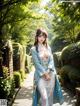 A woman in a blue and white kimono walking down a path.