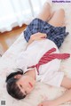 A woman laying on a bed wearing a school uniform.