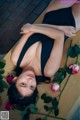 A woman laying on a wooden floor next to a bunch of roses.