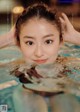 A woman in a swimming pool with her hands on her head.