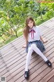 A woman in a school uniform sitting on a wooden deck.