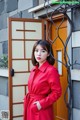 A woman in a red coat standing in front of a building.