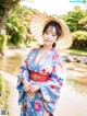 A woman in a blue kimono and a straw hat posing for a picture.