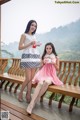 Two young women sitting on a wooden bench holding cups of tea.