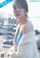 A woman in a blue dress and a white sweater on a beach.