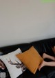 A woman laying on a black couch with two pillows.