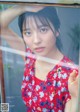 A woman in a red dress leaning against a window.